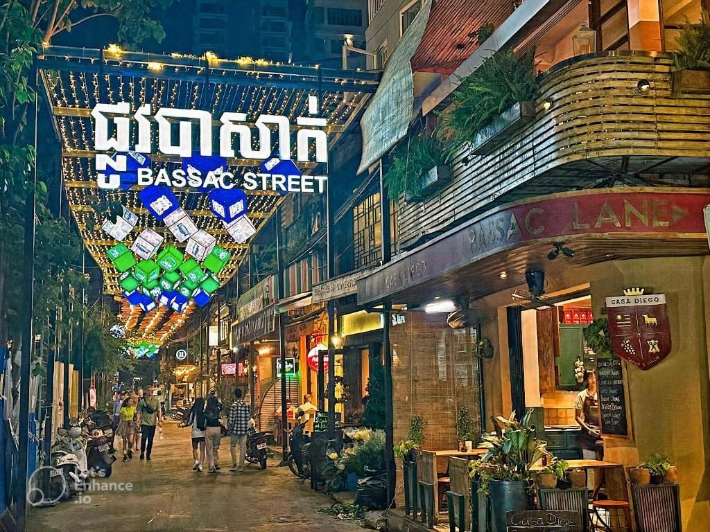 Bassac Lane, located in the heart of Phnom Penh, is a popular and trendy destination for nightlife. Unlike the hostess bar scene of Street 136, Bassac Lane is known for its stylish cocktail bars, chic lounges, and a vibrant, cosmopolitan atmosphere. It caters to a diverse crowd, including expatriates, tourists, and locals looking for a sophisticated night out.  Key Features Ambiance and Atmosphere:  Chic and Trendy: Bassac Lane is characterized by its narrow, tree-lined alleyways filled with small, stylish bars and eateries. The ambiance is relaxed yet lively, offering a more sophisticated alternative to other nightlife areas in Phnom Penh. Creative Decor: The bars and lounges often feature creative and unique decor, with some incorporating vintage elements, cozy seating, and artistic touches that add to the charm of the area. Bars and Lounges:  Diverse Offerings: Bassac Lane boasts a variety of bars, each with its distinct theme and specialty. From craft cocktails and fine wines to artisanal beers and exotic spirits, there’s something for everyone. Popular Spots: Some well-known bars in Bassac Lane include: Hangar 44: Known for its industrial-chic design and extensive cocktail menu. The Library: A cozy bar with a literary theme, offering a quiet escape with great drinks. Seibur: A Japanese-inspired bar famous for its sake and unique cocktails. Samai Distillery: Just a short walk away, it’s Cambodia’s first rum distillery and offers tasting nights and tours. Food and Dining:  Culinary Diversity: Alongside the bars, Bassac Lane features several eateries and restaurants offering a range of cuisines, from local Cambodian dishes to international fare. It’s common to find tapas, gourmet burgers, and fusion cuisine, making it a great place for foodies. Street Food: Nearby, there are street food vendors offering local snacks and quick bites, perfect for late-night munchies. Events and Entertainment:  Live Music: Many bars in Bassac Lane host live music nights, featuring local and international artists. Genres range from jazz and blues to rock and acoustic sets, adding to the dynamic nightlife experience. Themed Nights: Bars often organize themed nights, special events, and parties, keeping the scene fresh and exciting. Events like cocktail-making classes, wine tastings, and DJ nights are popular. Safety and Etiquette:  Safety: Bassac Lane is generally considered safe, but as with any nightlife area, it’s advisable to stay aware of your surroundings. The close-knit nature of the lane adds to the feeling of security, with many establishments being well-lit and frequented by friendly patrons. Etiquette: Dress codes are generally casual but trendy. Respectful behavior is expected, and it’s important to be considerate of others enjoying their night out. Tipping is appreciated but not mandatory. Accessibility and Location:  Central Location: Bassac Lane is centrally located, making it easily accessible from different parts of Phnom Penh. It’s close to major landmarks like the Independence Monument and the Royal Palace. Transport: Tuk-tuks and taxis are readily available, making it convenient to get to and from the area. Some visitors also prefer to walk from nearby hotels and attractions. Summary Bassac Lane offers a unique and upscale nightlife experience in Phnom Penh, distinct from the more boisterous scenes of other areas. With its stylish bars, diverse dining options, and vibrant atmosphere, it’s a perfect spot for those looking to enjoy a sophisticated night out in the city. Whether you’re in the mood for craft cocktails, live music, or gourmet food, Bassac Lane has something to offer for everyone.